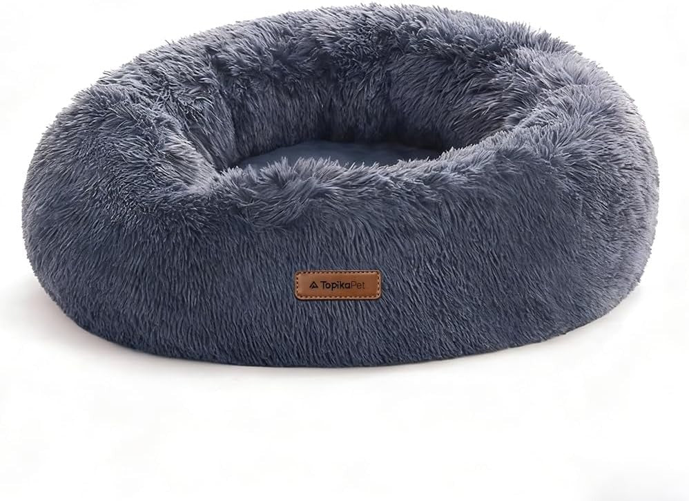 White Pomeranian dog resting in Topika Calming Donut Dog Bed